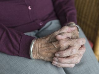 Elderly persons hands clasped together